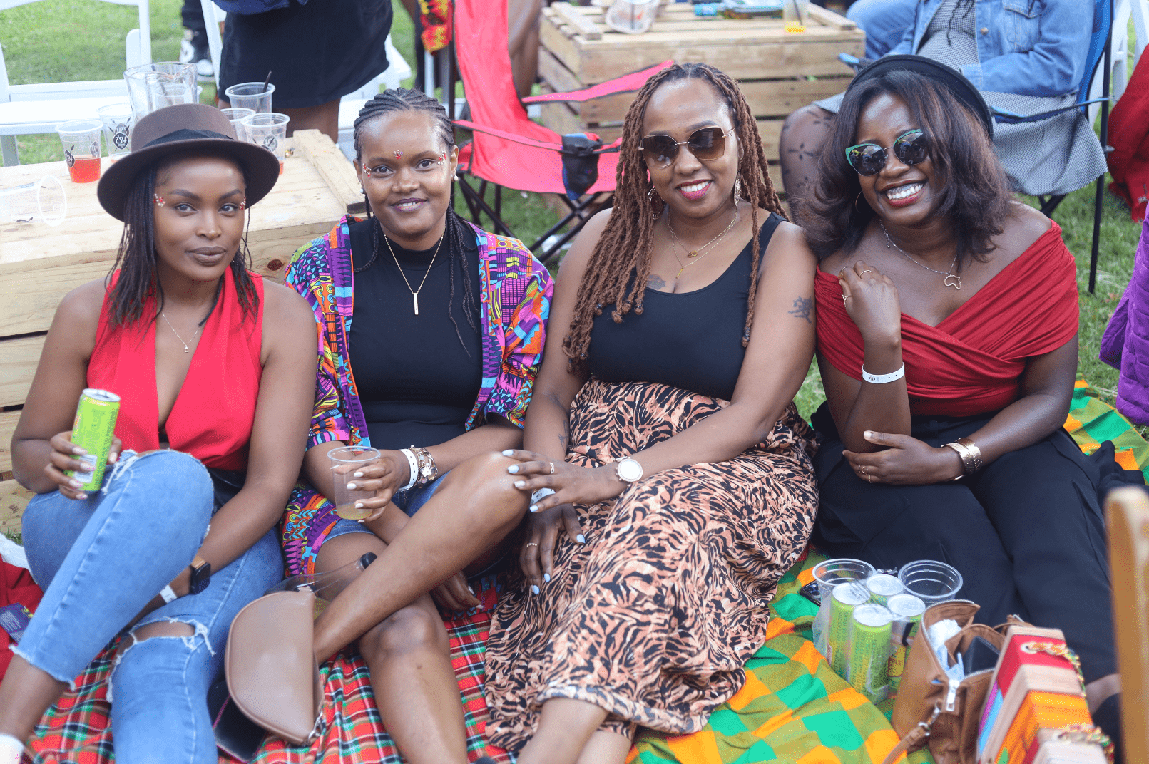 Four women smiling while sitting on a picnic blanket outdoors